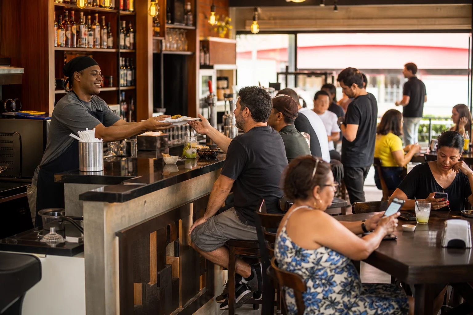Balcão de lanchonete movimentado, com clientes conectados ao celular.