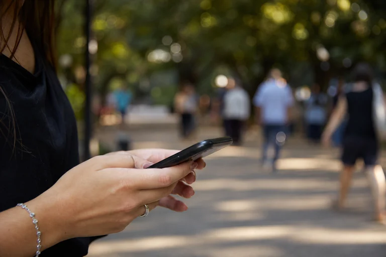 Cidadã usando o celular em praça pública.