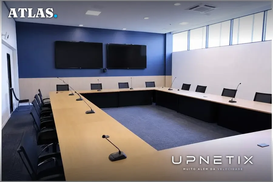 Sala de reunião de diretoria com mesa em U, microfones e cadeiras vazias