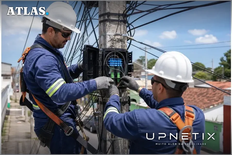 Técnicos instalando fibra óptica em postes para melhorar conectividade em município brasileiro.